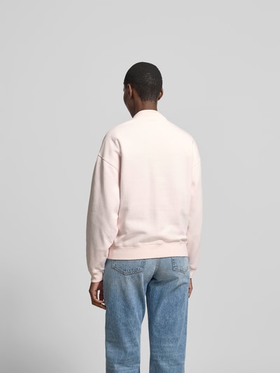 Frauenmodel trägt Regular Fit Sweatshirt mit Logo-Detail von Anine Bing aus reiner Baumwolle in hellem Rosa, elastische Abschlüsse, Rückenlänge bei Größe S 65 cm, Ganzkörperansicht Rückansicht.