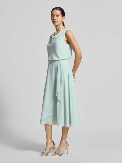 Modelka kobieca nosi Knielanges Cocktailkleid mit Wasserfall-Ausschnitt od Christian Berg Cocktail, szyfon, taliowany, długość do kolan, lejący dekolt, szerokie ramiączka, kopertowy styl, zapięcie na haftkę i zamek błyskawiczny z tyłu, długość tyłu w rozmiarze 36: 120 cm, szerokość w rozmiarze 36: 45 cm, pastelowy miękki odcień, lekko rozkloszowany dół, faktura gładka, widok całej sylwetki z przodu.
