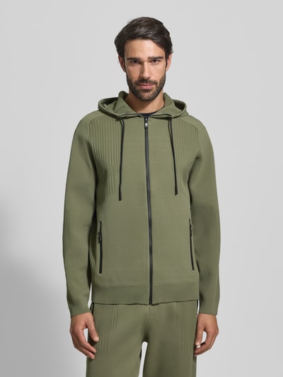 Männermodel trägt Regular Fit Trainingsjacke mit Jacquard Elementen Modell 'ACTIVE PUSH' van BOSS Green in olijfgroen, unikleur, lange mouwen, structuurstof, ritssluiting, capuchon; Ganzkörperansicht von vorne.