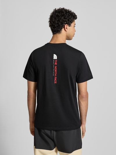 Männermodel trägt Regular Fit T-Shirt aus Baumwoll-Mix Modell 'VERTICAL' von The North Face, schwarzer Stoff, Label-Print, Rückenlänge 71 cm, Ganzkörperansicht Rückansicht.