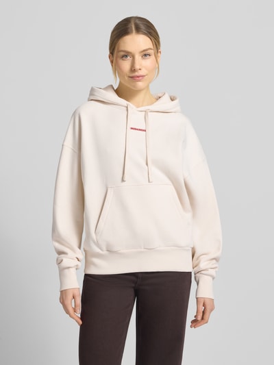 Vrouwenmodel draagt Oversized Hoodie uit pure katoen model 'FRANCISARAA DIFFERENCE' van Armedangels in effen kleur met labelopschrift, kangoeroezak, capuchon met tunnelkoord, lange mouwen en geribbelde boorden, sweatstof, voorkant totaalaanzicht.