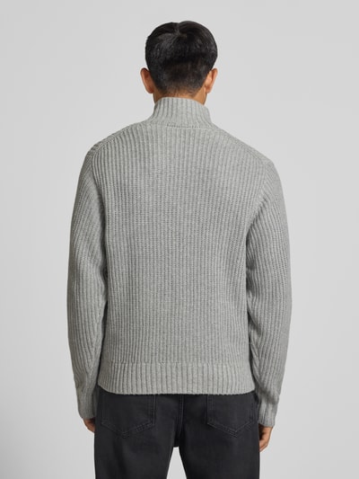 Männermodel trägt Troyer mit Brustleistentasche Modell 'DETROIT' von Carhartt Work In Progress in Grau, Strukturstrick, Ganzkörperansicht Rückansicht. Material-Mix mit Woll-Anteil, Regular Fit, Troyer-Kragen, Label-Patch, Rückenlänge 68 cm, Ärmellänge 56 cm.