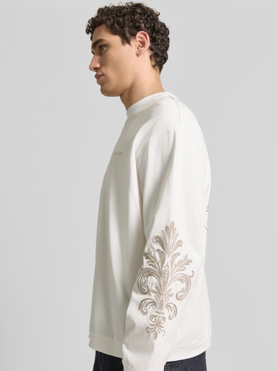 Männermodel trägt Oversized Sweatshirt aus Baumwolle von Don´t Waste Culture in Creme mit Florale-Stickereien, Ganzkörperansicht von vorne.