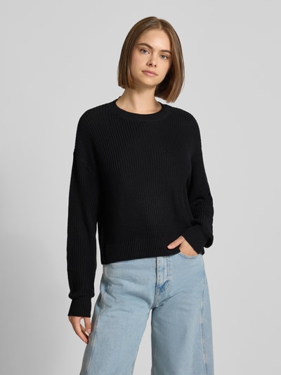 Modelka nosi czarny Relaxed Fit Pullover aus Baumwoll-Mix Modell 'Maysa' od NOISY MAY®, faktura dzianiny, dekolt okrągły, całkowity widok z przodu.
