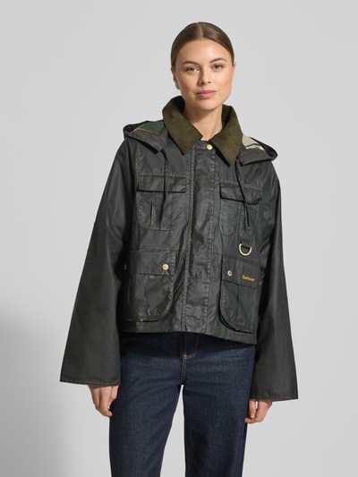 Kobiece model nosi Regular Fit Funktionsjacke aus reiner Baumwolle Modell 'LIZA' von Barbour, jednolity kolor, stójka, odpinany kaptur, napisy z logo, metalowe akcenty, długi rękaw z brzegiem, kieszenie na piersi i bokach, tkanina woskowana, bawełna, widok całej sylwetki z przodu.