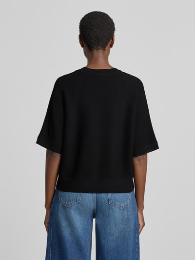 Frauenmodel trägt schwarzen Relaxed Fit Pullover aus Viskose-Mix Modell 'Thamira' von MSCH Copenhagen, Strick-Optik, Ganzkörperansicht Rückansicht.