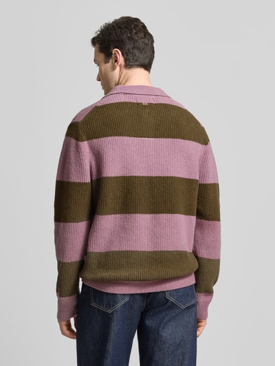 Männermodel trägt Strickpullover mit Polo-Kragen Modell 'Kimse' von Wood Wood in Lila und Oliv, Baumwoll-Mix mit Woll-Anteil, Gerader-Schnitt, Rückenlänge 71 cm bei Größe M, Ganzkörperansicht Rückansicht.