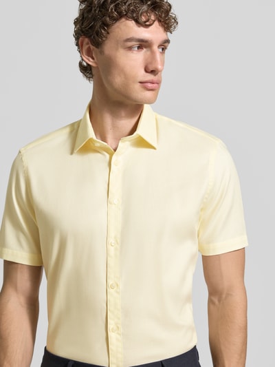 Männermodel trägt Slim Fit Business-Hemd aus Baumwolle mit Kentkragen von Jake*s in Hellgelb, Knopfleiste, Nahaufnahme Oberkörper.