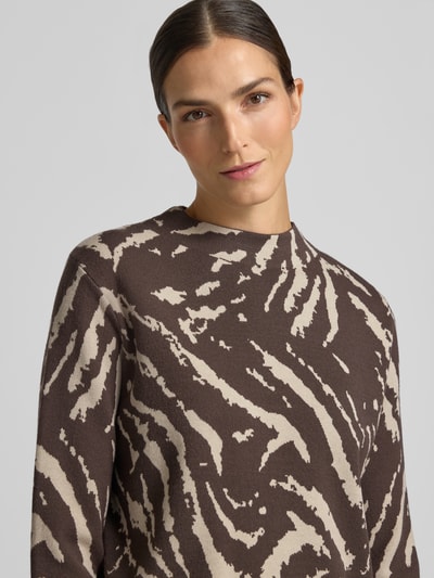 Frauenmodel trägt Strickpullover aus Viskose-Mix im Allover-Look von COMMA, braun-beige Muster, Regular Fit, Stehkragen, Nahaufnahme Oberkörper.