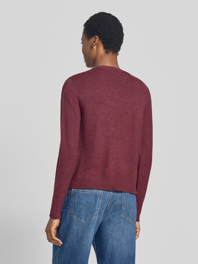 Frauenmodel trägt Strickjacke aus Viskose-Mix von VILA in Bordeaux mit geripptem Bund und Ärmelabschlüssen, gerade Passform, Ganzkörperansicht Rückansicht.