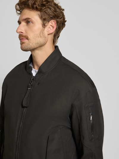Männermodel trägt Regular fit heren jack van katoenmix model 'Pulse' van g-lab in zwart met opstaande kraag, mouwzak, steekzakken, elastische boorden, zichtbare structuur, nahaufnahme bovenlichaam. Ruglengte maat M: 70 cm, schouderbreedte: 55 cm, borstwijdte: 50 cm, mouwlengte: 61 cm.