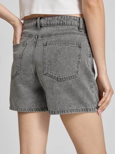Frauenmodel trägt Regular Fit Jeansshorts aus Baumwoll-Mix Modell 'ABBI' von Pieces in grauer Denim-Optik mit 5-Pocket-Design, Ganzkörperansicht Rückansicht.