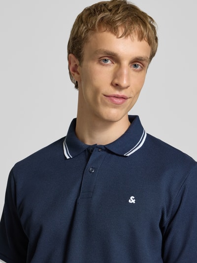 Männermodel trägt Regular Fit Poloshirt mit Strukturmuster Modell 'AUSTIN' von Jack & Jones, Baumwoll-Mix, Knopfleiste, Nahaufnahme Oberkörper.