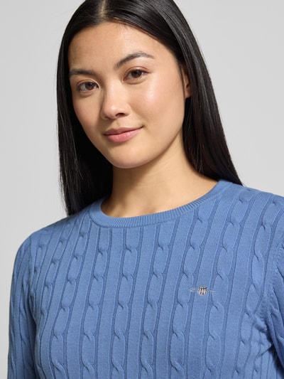 Modelka kobieca nosi Strickpullover mit Zopfmuster und Label-Stitching od Gant, niebieski, okrągły dekolt, wąski krój, bawełniany mix, zbliżenie górnej części ciała.