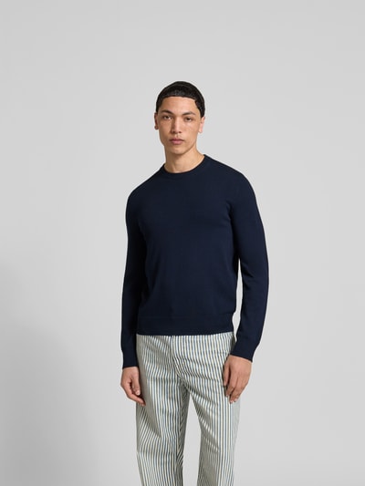 Männermodel trägt Slim Fit Pullover aus Woll-Mix von Filippa K, dunkelblau, Strick-Optik, Rundhalsausschnitt, Langarm, Ganzkörperansicht von vorne.