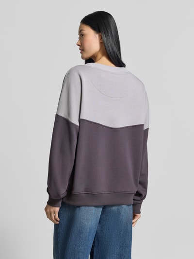 Frauenmodel trägt Oversized Sweatshirt aus reiner Baumwolle von miss goodlife in Grau und Dunkellila mit gerippten Abschlüssen, Ganzkörperansicht Rückansicht.