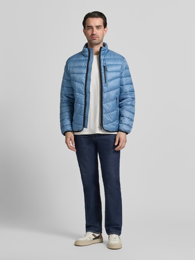 Männermodel trägt Regular Fit Steppjacke mit Stehkragen von Tom Tailor in Hellblau, unifarben, langer Arm, elastische Abschlüsse, Ganzkörperansicht von vorne.