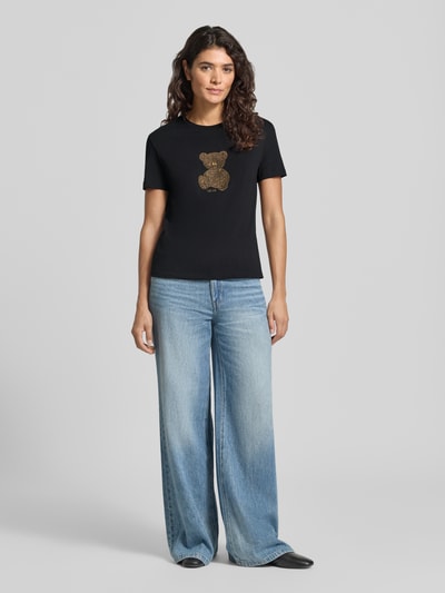Kobieta modelka nosi Slim Fit T-Shirt mit Ziersteinbesatz od Liu Jo White z bawełny, Motyw, okrągły dekolt, długość tyłu w rozmiarze S: 57 cm, widok całej sylwetki z przodu