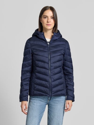 Modelka nosi Regular Fit Puffer Jacket mit Reißverschlusstaschen von Jake*s Casual, jednokolorowy efekt, kaptur, krój regular fit, długi rękaw, kieszenie zapinane na zamek błyskawiczny, wykończenie materiału pikowane, widok całej sylwetki z przodu.