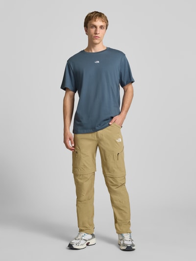 Männermodel trägt T-Shirt mit Logo-Stitching von The North Face aus Reine Baumwolle, Gerader-Schnitt, Gerippter Rundhalsausschnitt, Ganzkörperansicht von vorne.
