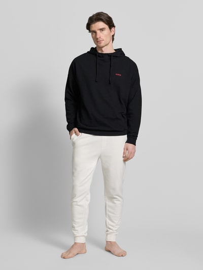 Męski model nosi Relaxed Fit Hoodie aus Baumwoll-Mix od HUGO, jednokolorowy, wyhaftowane logo, długi rękaw, faktura wafla, Ganzkörperansicht von vorne.