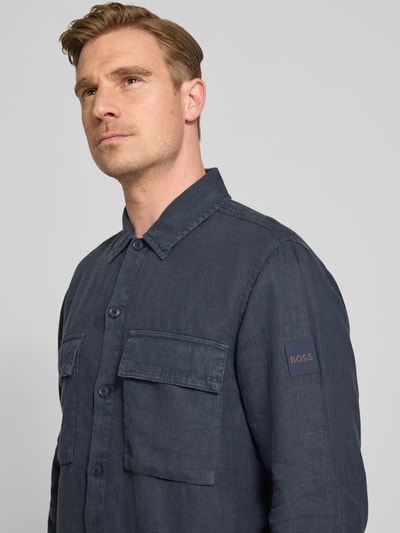 Męski model nosi Relaxed Fit Freizeithemd aus reinem Leinen Modell 'LOCKY' od BOSS Orange, granatowy len, kieszenie na piersi, flammgarn, unikatowa faktura, widok z przodu, zbliżenie na górę ciała.