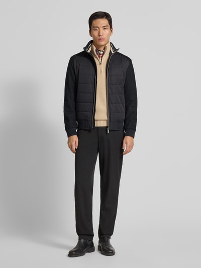 Mannelijk model draagt Jacke mit Stehkragen van Christian Berg Men in zwart, regular fit, opstaande kraag, ritssluiting, ritszakken, ribboorden, ruglengte maat M 26 cm, schouderbreedte 19 cm, borstwijdte 19 cm, mouwlengte 26 cm. Ganzkörperansicht van voren.
