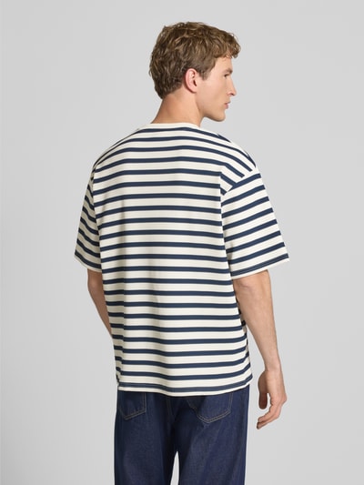 Männermodel trägt Oversized T-Shirt mit Rundhalsausschnitt Modell 'Gael' von Redefined Rebel, blau-weiß gestreift, Elastischer-Material-Mix, Oversized-Fit, Rückenlänge bei Größe M 75 cm, Ganzkörperansicht Rückansicht.