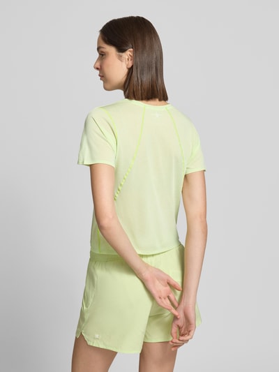 Frauenmodel trägt Cropped T-Shirt mit Rundhalsausschnitt Modell 'SHKOUT' von Salomon in Pastellgrün, taillierte Passform, Rückenlänge bei Größe S 47 cm, Raglanärmel, Ganzkörperansicht Rückansicht.