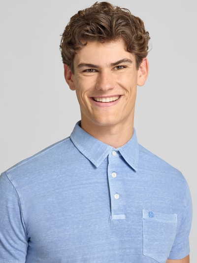 Männermodel trägt Slim Fit Poloshirt mit Brusttasche von Superdry in Hellblau, Baumwoll-Leinen-Mix, Knopfleiste, Nahaufnahme Oberkörper. Rückenlänge bei Größe M: 67 cm.