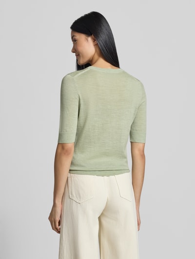 Frauenmodel trägt Regular Fit Pullover aus reiner Schurwolle Modell 'Farbella' von BOSS in zartem Grün zu cremefarbener Hose, Ganzkörperansicht Rückansicht, Damen Pullover von BOSS.