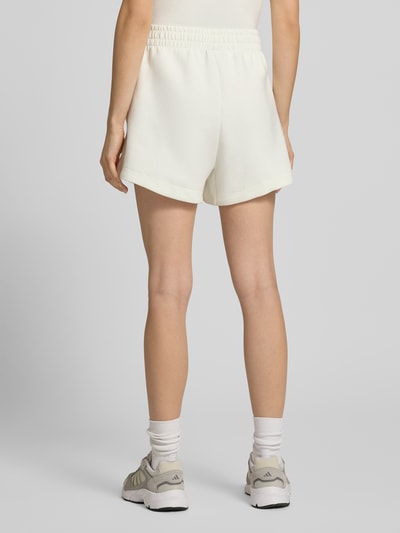 Frauenmodel trägt Shorts mit Label-Print von adidas Sportswear in Weiß mit elastischem Bund aus Material-Mix, lockerer Schnitt, Ganzkörperansicht Rückansicht.