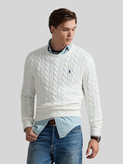Männermodel trägt Regular Fit Strickpullover aus reiner Baumwolle von Polo Ralph Lauren, weiß, Zopfmuster, Rundhals, Logo, Ganzkörperansicht von vorne.
