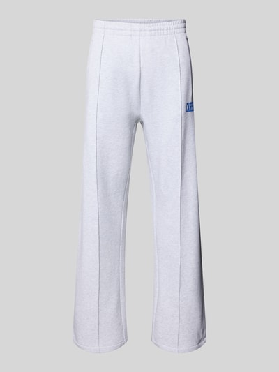 Produktfoto, Sweatpants mit elastischem Bund und Label-Print von Carhartt Work In Progress aus reiner Baumwolle, wide leg, hellgrau, sichtbare Längsnähte, blauer Label-Print auf dem Oberschenkel, weiche Textur, Modell 'Pond Corps', Innenbeinlänge Größe M 72 cm