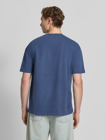 Męski model nosi t-shirt z bawełny w kolorze niebieskim, krój regular fit, T-Shirt mit Rundhalsausschnitt Modell 'JOEL' od Samsøe Samsøe, długość tyłu w rozmiarze M: 72 cm, widok całej sylwetki z tyłu