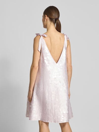 Frauenmodel trägt Relaxed Fit Kleid mit Allover-Paillettenbesatz von Jake*s Cocktail in hellem Rosé, V-Ausschnitt, Zierschleifen, ärmellos, Minilänge, Rückenausschnitt, schimmernde Oberfläche, Ganzkörperansicht Rückansicht.
