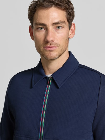 Männermodel trägt Jacke mit Stretch-Anteil von Paul Smith in Dunkelblau, sichtbarer Reißverschluss, Nahaufnahme Oberkörper.