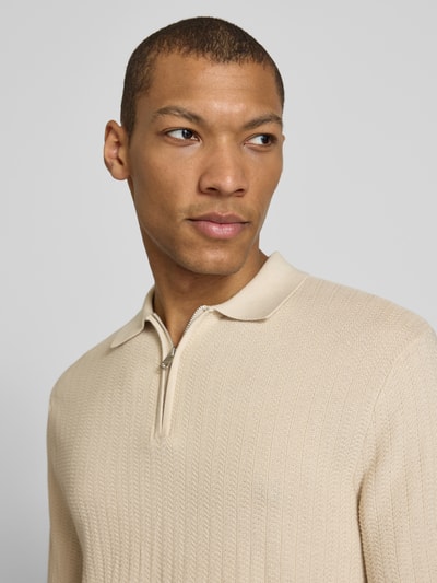 Męski model nosi Regular Fit Poloshirt aus reiner Baumwolle Modell 'CRAN' od SELECTED HOMME, beżowy, strukturowana dzianina, z krótkim zamkiem, krój regular fit, kołnierzyk polo, krótki rękaw, zbliżenie na górną część ciała.