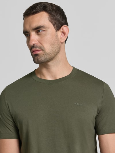 Męski model nosi Regular Fit T-Shirt aus reiner Baumwolle von s.Oliver RED LABEL, kolor oliwkowy, gładka tekstura, zbliżenie górnej części ciała