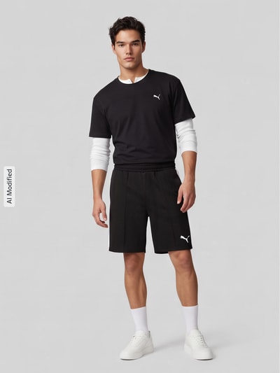 Männermodel trägt Relaxed Fit Sweatshorts mit Baumwoll-Anteil von PUMA, Herren Sweatshorts, schwarz, Ganzkörperansicht von vorne, KI-modifiziertes Bild