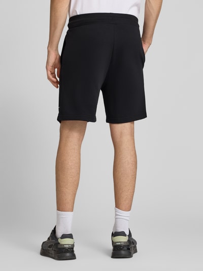 Männermodel trägt Regular Fit Shorts mit Eingrifftaschen von The North Face, schwarzer Baumwoll-Mix, Gesäßtaschen, Ganzkörperansicht Rückansicht.