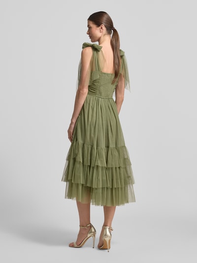 Modelka kobieca ma na sobie Cocktailkleid aus Tüll im Stufen-Look od LACE & BEADS, sukienka koktajlowa z tiulu, linia a, sukienka midi, efekt stopniowania, drapowania, długość tyłu w rozmiarze s: 103 cm, szerokość w rozmiarze s: 31 cm, całość w zielonym kolorze, wyraźna faktura tiulu, widoczne warstwowe falbany, widok całej sylwetki z tyłu