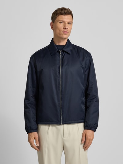 Männermodel trägt Regular Fit Blouson mit Logo-Muster Modell 'H-CRESTELL' von BOSS in Dunkelblau, Allover-Muster, Umlegekragen, Reißverschluss, Label-Applikation, elastische Langarmabschlüsse, Tunnelzug innen, seitliche Eingrifftaschen, Ganzkörperansicht von vorne.
