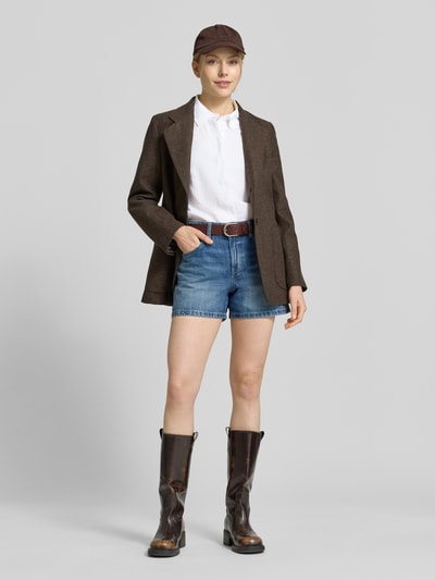 Frauenmodel trägt Regular Fit Leinenbluse mit verdeckter Knopfleiste von Mango in Weiß, kombiniert mit Jeansshorts und braunem Blazer, reine Leinen-Qualität, verdeckte Knopfleiste, Ganzkörperansicht von vorne.