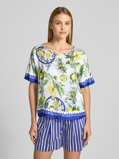 Vrouwenmodel draagt Relaxed Fit T-shirt aus reiner Viskose mit floralem all-over print van Marc Cain, dames t-shirt, zuiver viscose, relaxed fit, all-over bloemenprint, ronde hals, halflange mouwen, ruglengte bij maat 36: 59 cm, mouwlengte bij maat 36: 26 cm, frisse kleuren, blauwe accenten, vooraanzicht halfbody.