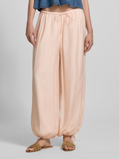 Frauenmodel trägt Relaxed Fit Stoffhose aus Viskose-Mix von Gina Tricot, semitransparent, elastischer Bund mit Tunnelzug, Nahaufnahme Unterkörper.