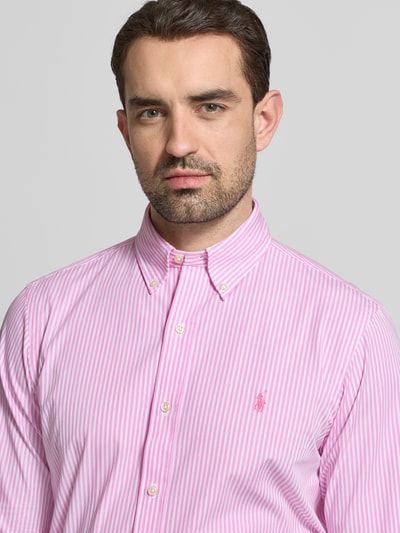 Männermodel trägt Regular Fit Freizeithemd aus Baumwoll-Mix von Polo Ralph Lauren mit pink-weißen Streifen und Logo-Stitching, Nahaufnahme Oberkörper.