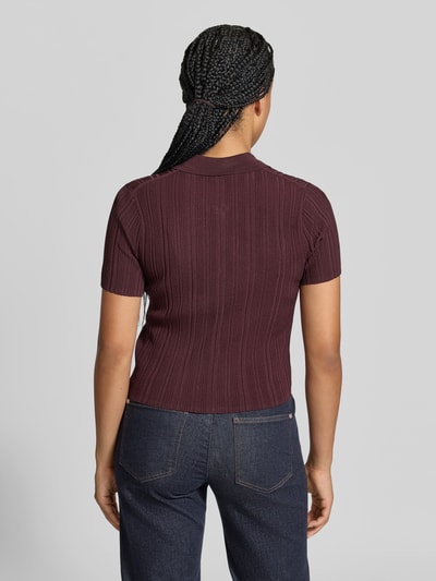 Frauenmodel trägt Shirt mit Zweiwege Reißverschluss von Victoria Beckham in dunklem Bordeaux, strukturierte Strickoptik, Ganzkörperansicht Rückansicht.