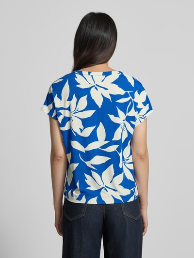 Frauenmodel trägt Relaxed Fit T-Shirt aus Viskose-Mix von s.Oliver RED LABEL mit floralem Allover-Muster in Blau und Weiß, Jerseystruktur, Ganzkörperansicht Rückansicht.