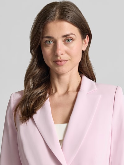 Vrouwenmodel draagt Blazer mit Reverskragen und doppelreihigem Knopfverschluss van Rinascimento in lichtroze, getailleerde fit, stretch-materiaalmix, reverskraag, dubbele knoopsluiting, klepzakken, ruglengte maat S 53 cm, close-up bovenlichaam.